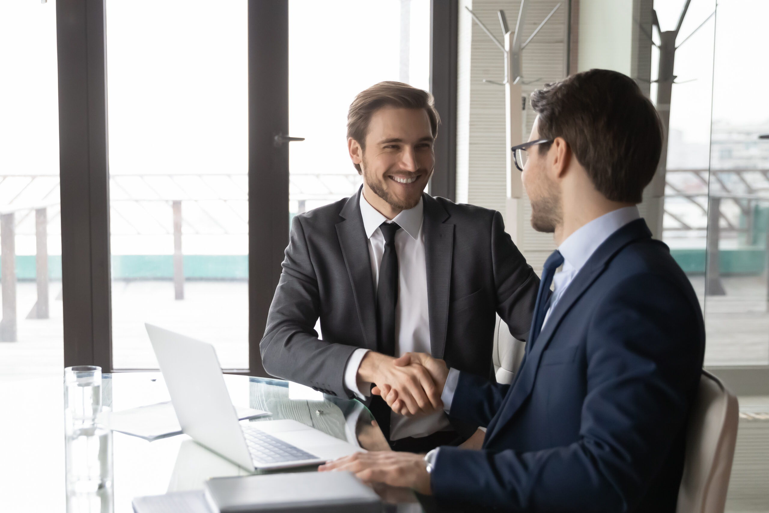 Two business partners shaking hands in agreement during a meeting at the office.